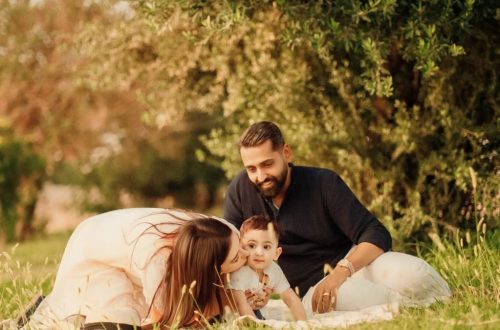 A joyful family with parents and a baby enjoying a sunny day outdoors on a picnic.